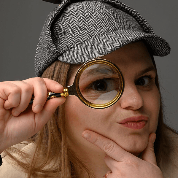 Monika Ciechomska w czapce detektywa z lupą powiększającą przy oku