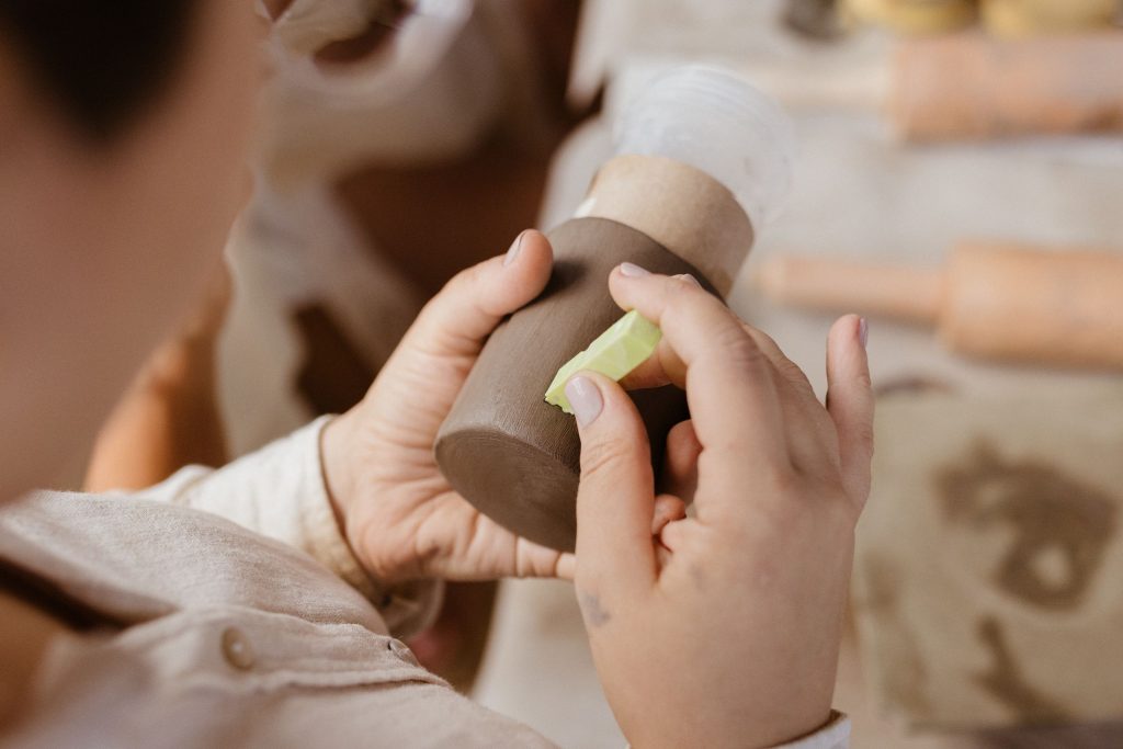 A person skillfully crafting pottery in an indoor setting, showcasing detailed handwork and craftsmanship.