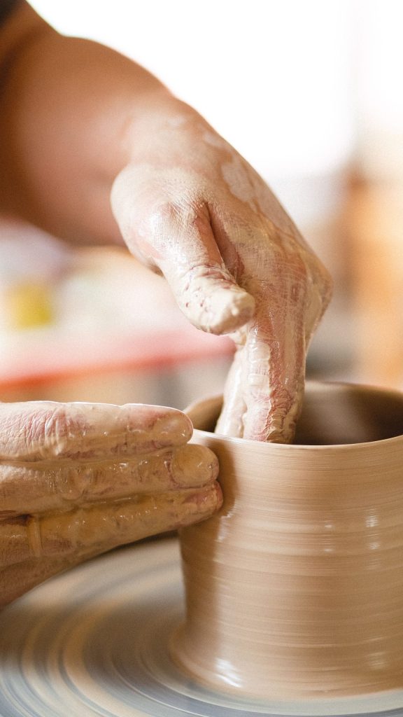 Artisan shaping clay on pottery wheel, focused on craftsmanship and skill.