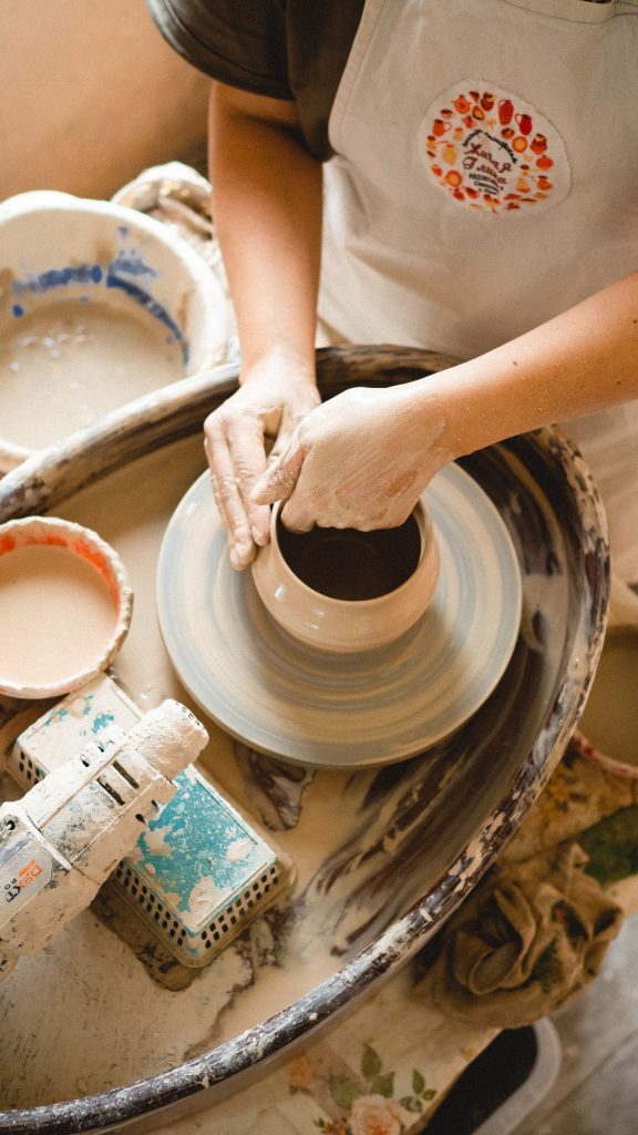 Close-up of hands shaping clay on a pottery wheel in a studio setting.