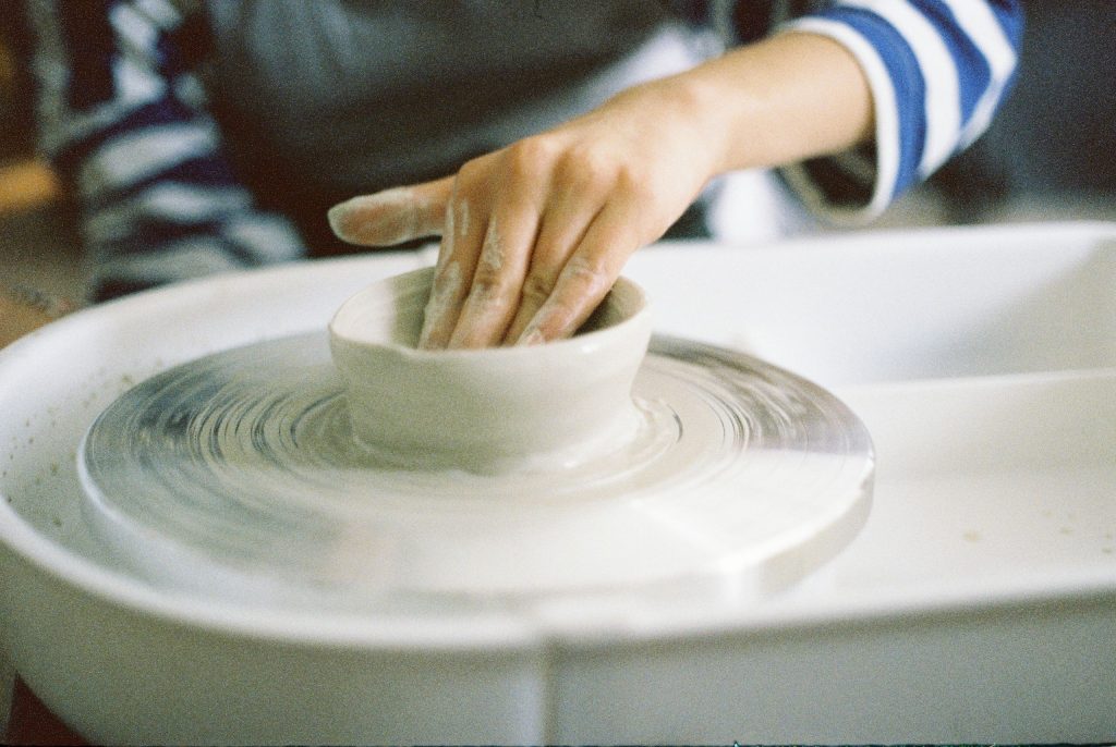 Close-up of hands shaping clay on a pottery wheel, showcasing the art of handmade ceramics.