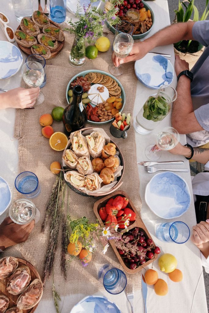 Top view of a lively outdoor brunch with friends, featuring diverse dishes and fresh drinks.